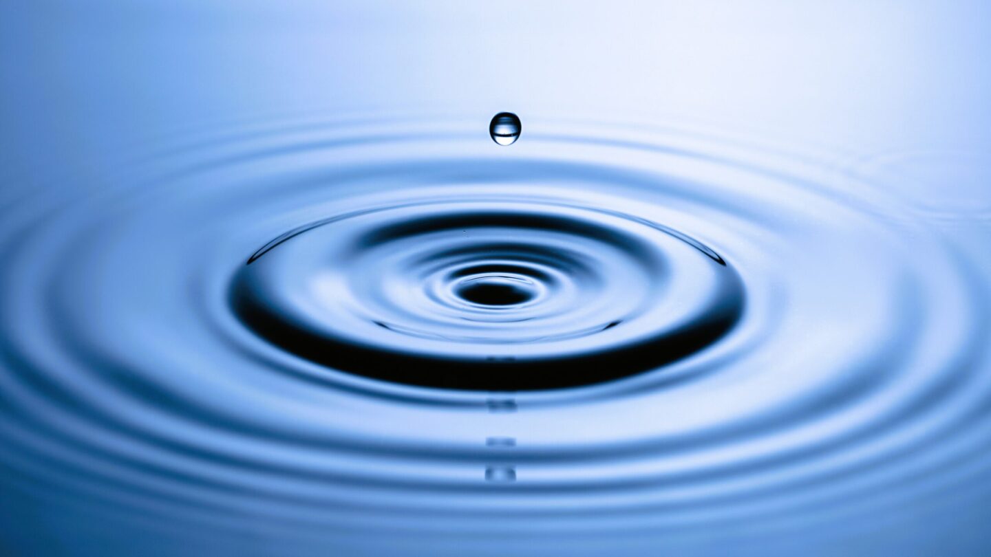 Blue water drop falling, macro splash. natural background.